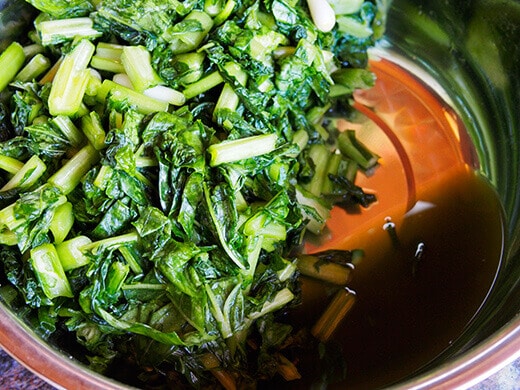 Knead the veggies until the leaves are wilted, the volume is reduced in half, and there is liquid pooling at the bottom