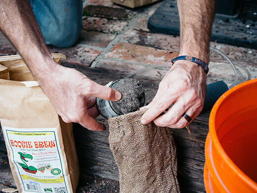 Pour Boogie Brew compost into burlap sack