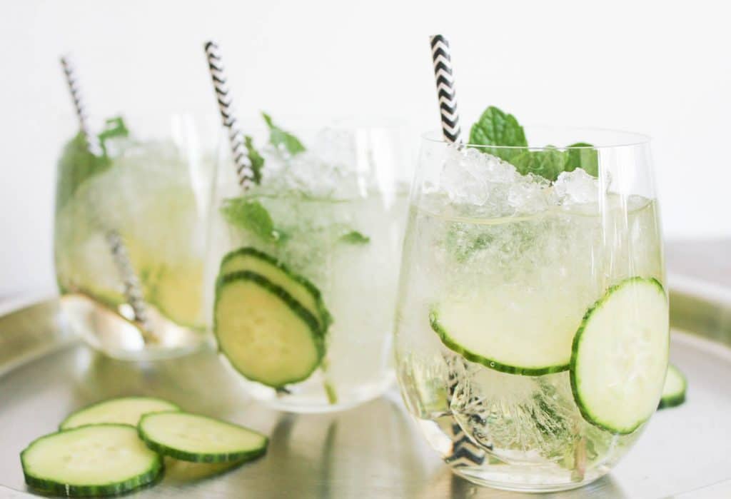 Three glasses of Cucumber Mint sparklers garnished with cucumber slices and mint. 