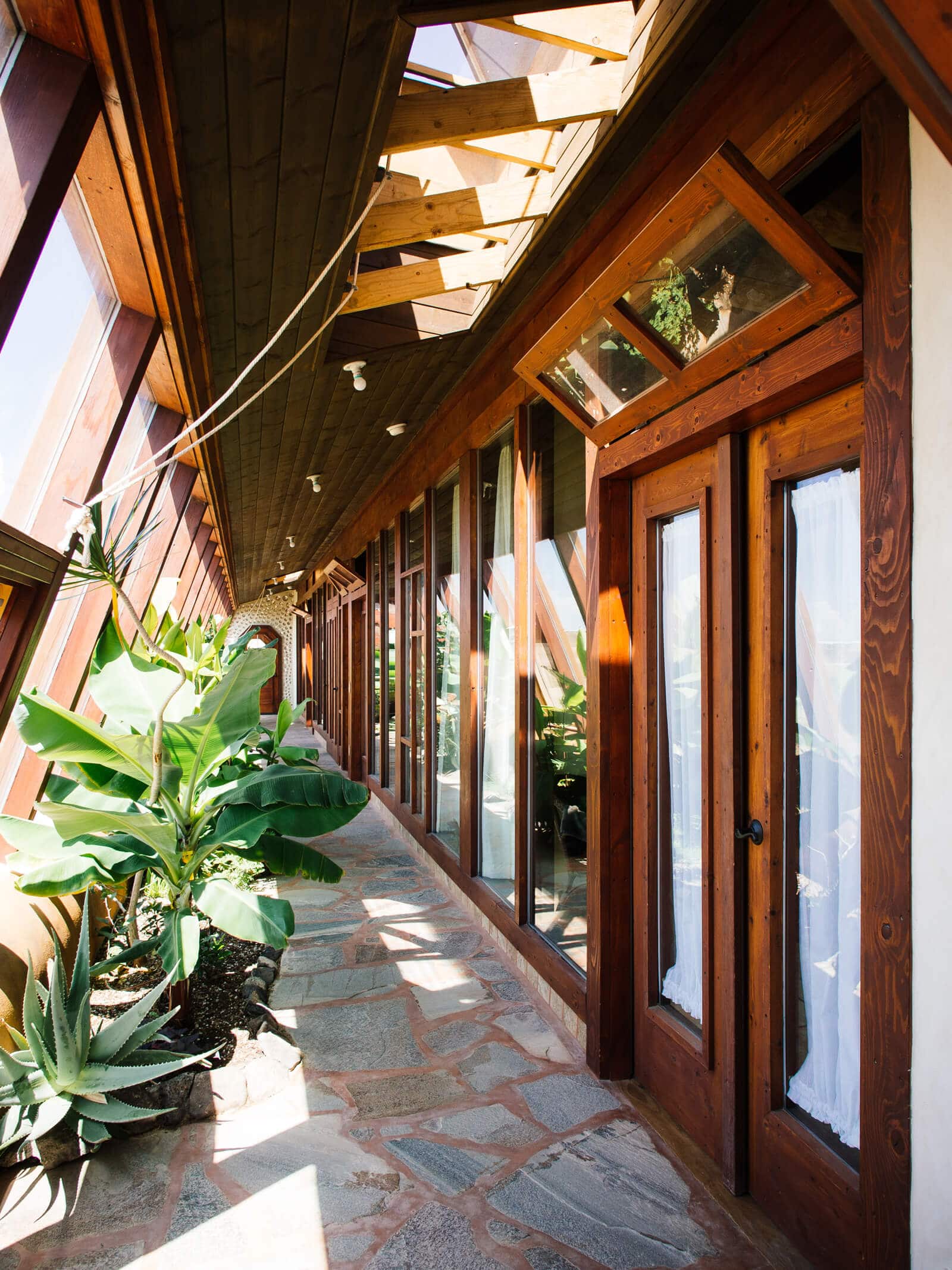 The south-facing greenhouse is a defining feature of Earthship Biotecture's passive solar house plans