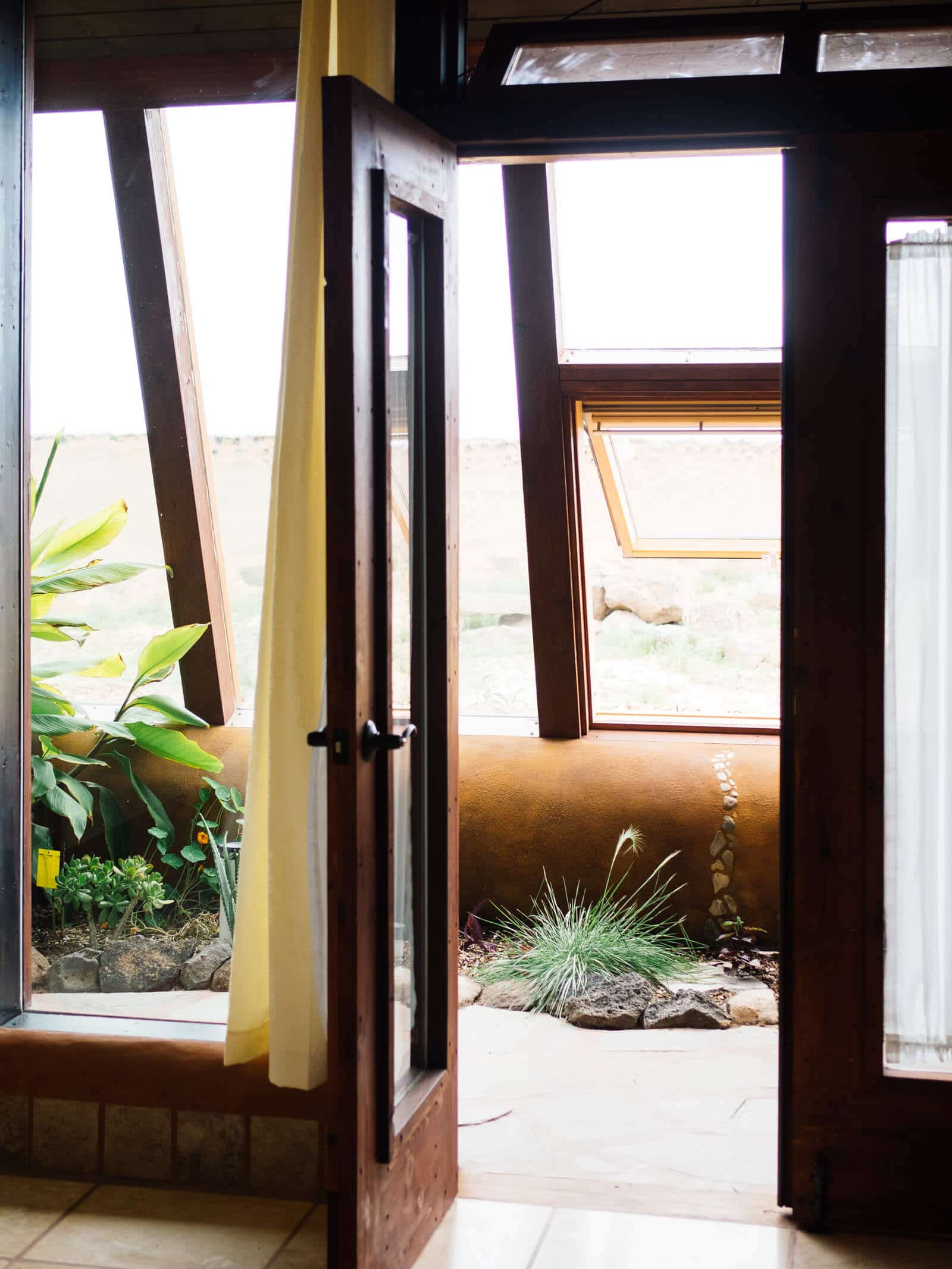 The greenhouse is attached to the interior living spaces in an Earthship