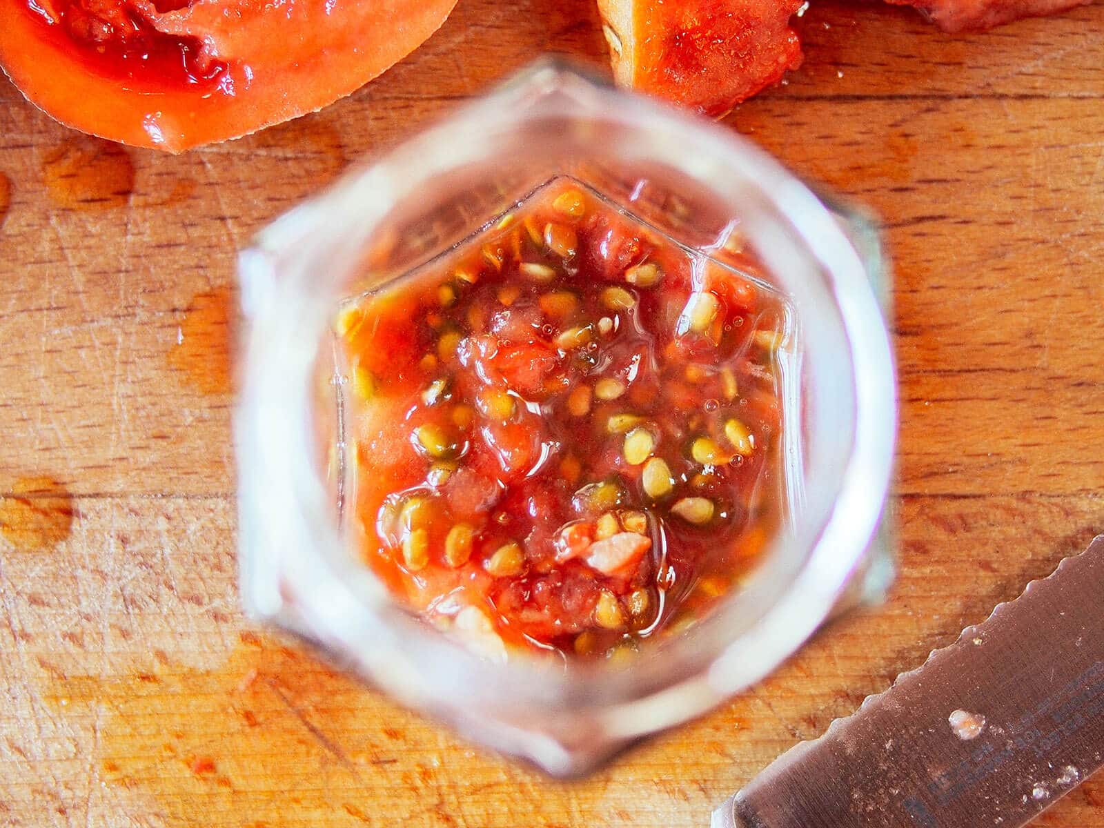 Overhead shot of tomato seeds scooped out into a jar