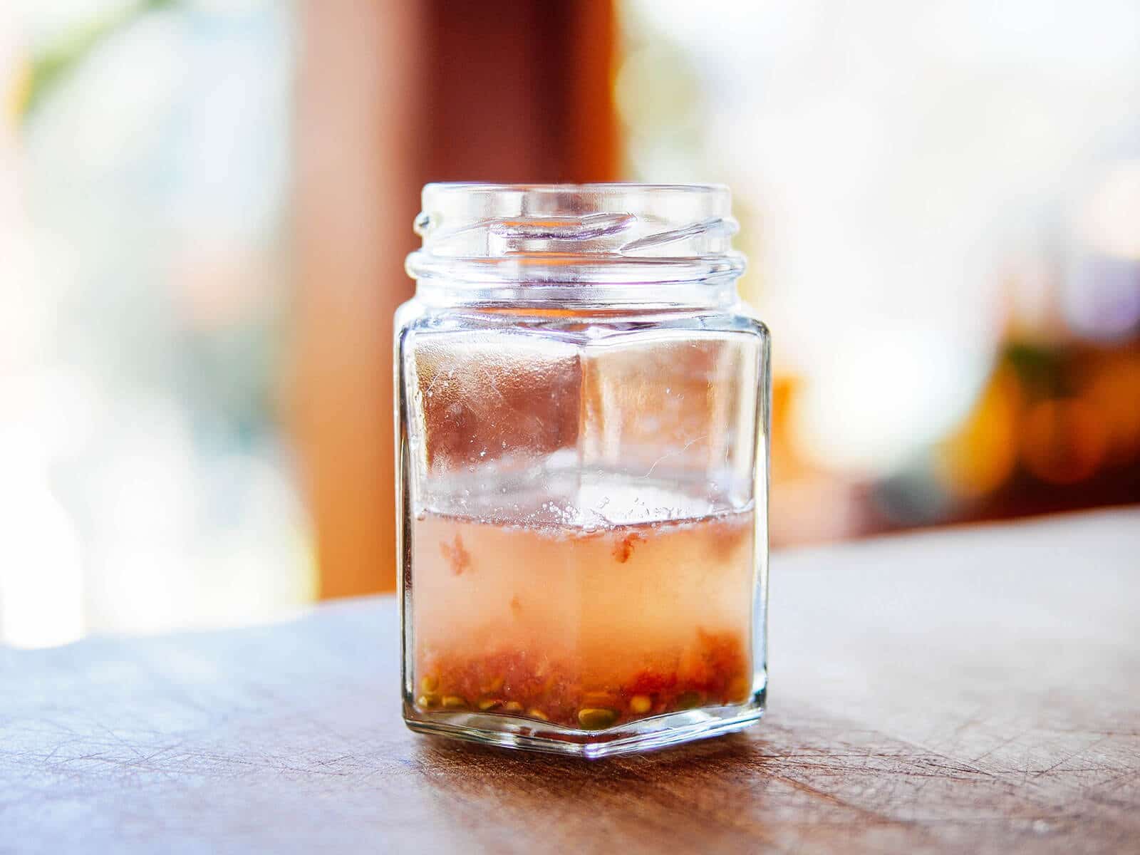 Tomato seeds going through fermentation in a jar