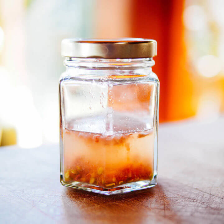 A lidded jar holding tomato seeds while they're fermenting in water