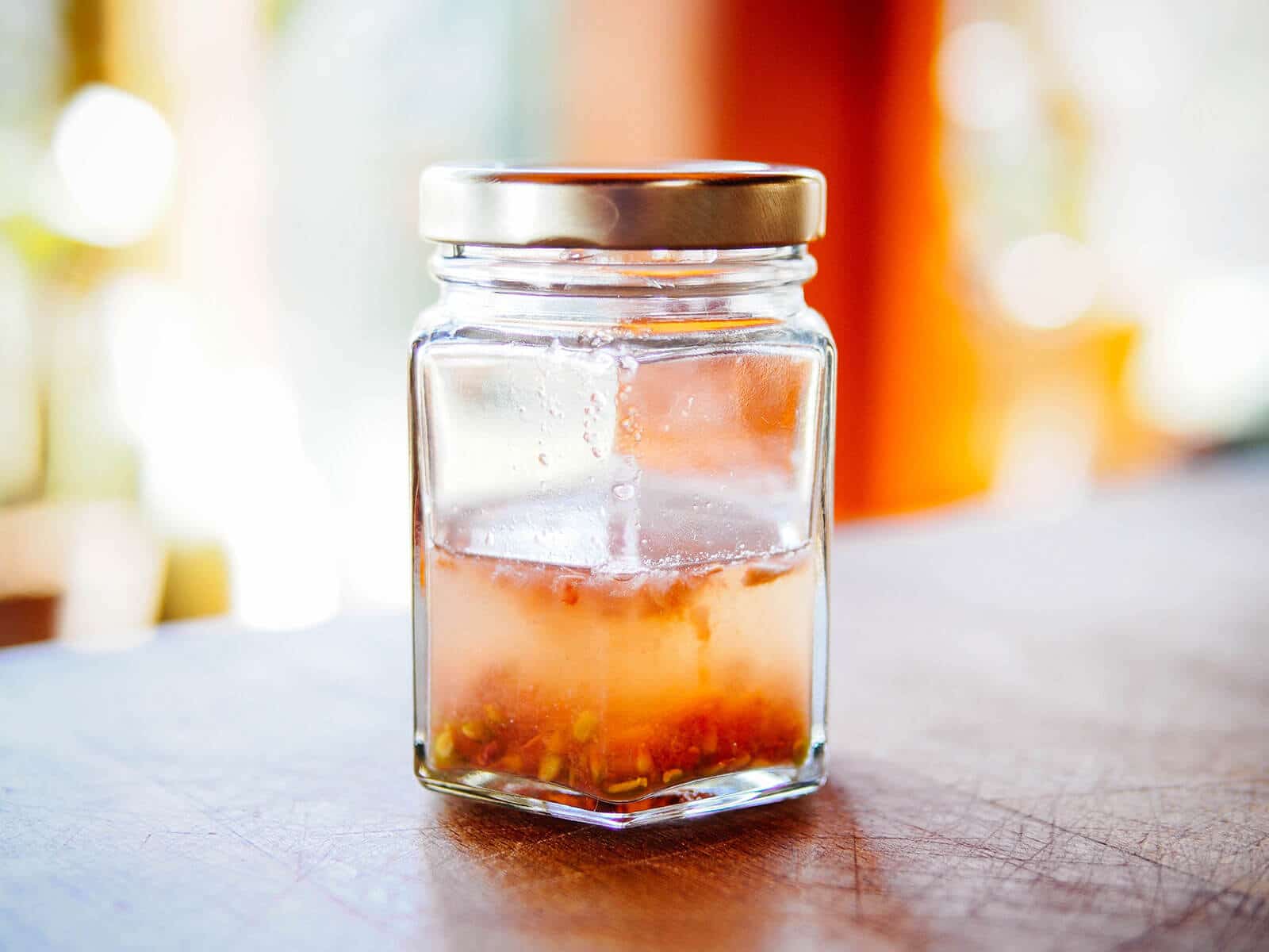 A lidded jar holding tomato seeds while they're fermenting in water