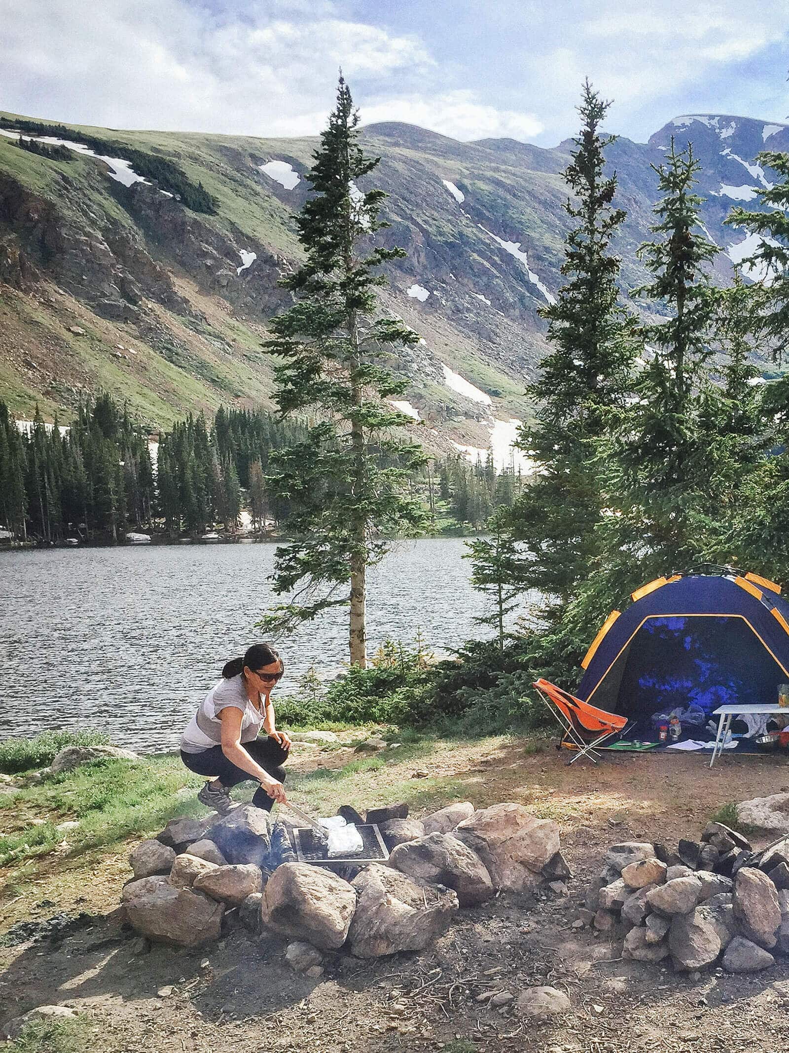 Garden Betty grilling over a fire near a lake in the backcountry