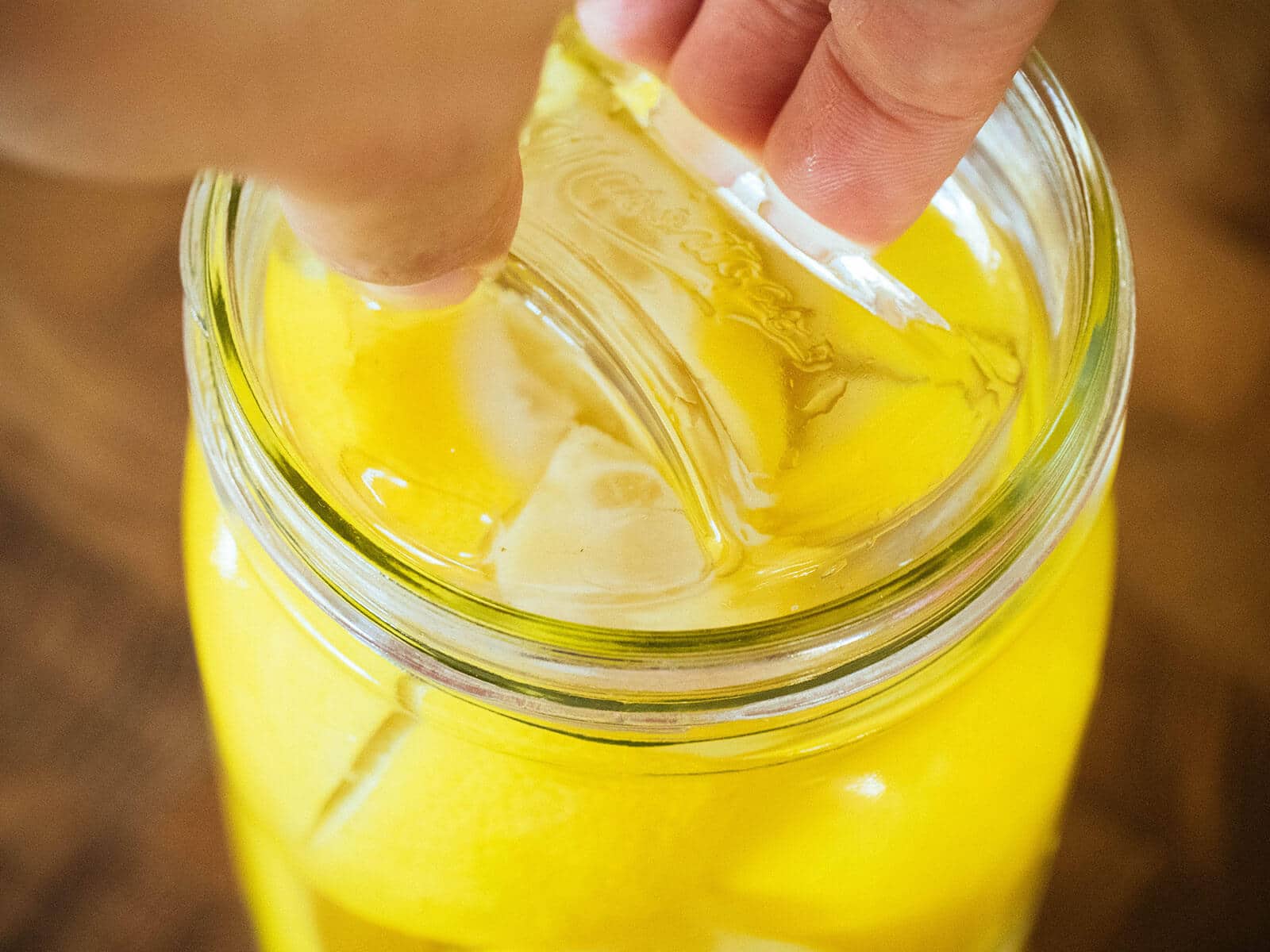 Hand adding a glass fermenting weight to a jar of lemons