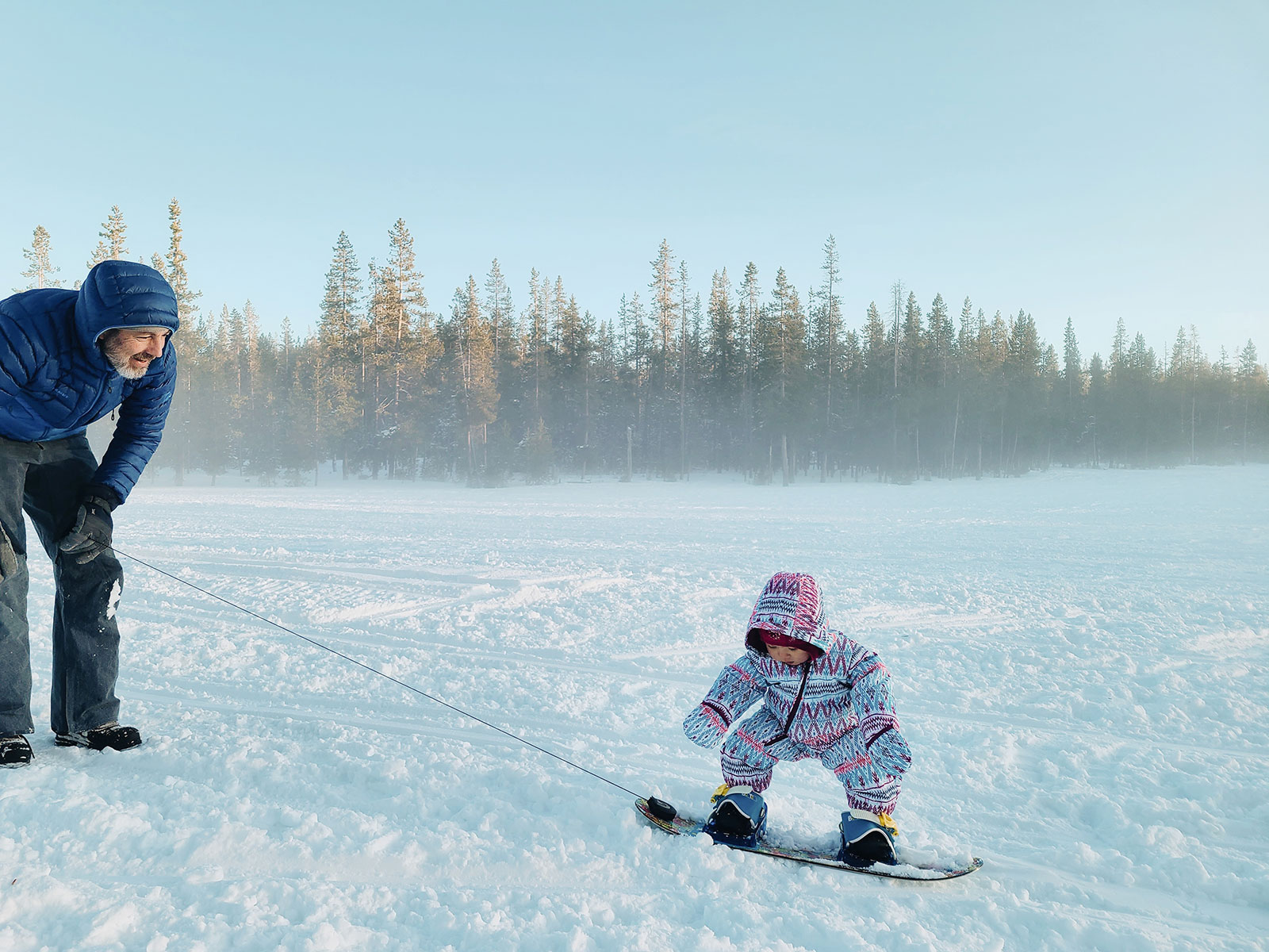 A 1-year-old baby squatting naturally as she learns how to balance on a snowboard