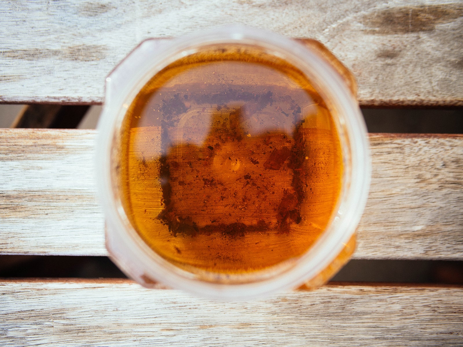 Overhead view of a jar of vinegar with rust flakes floating in it