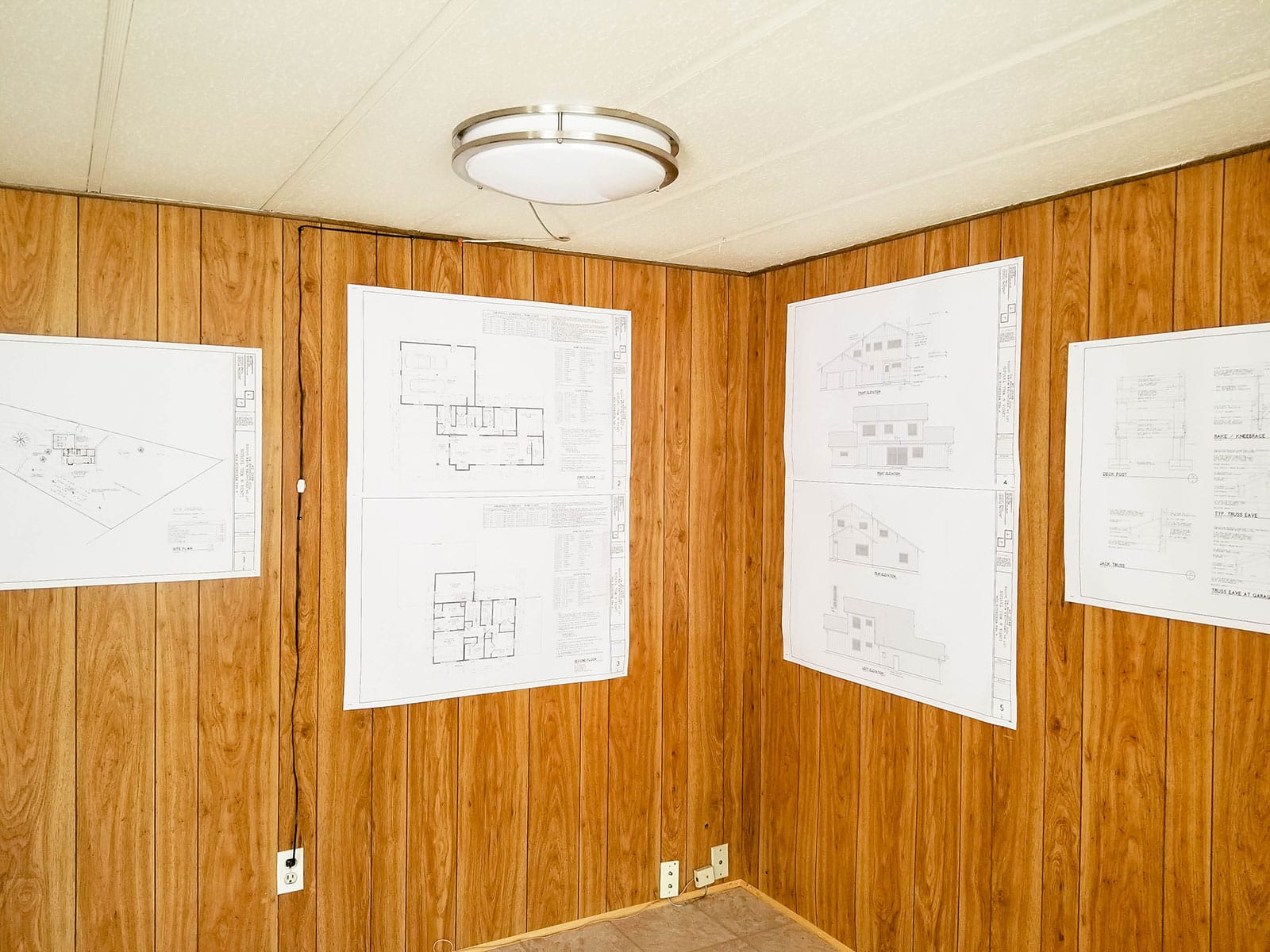 House plans hung up on wood-paneled walls