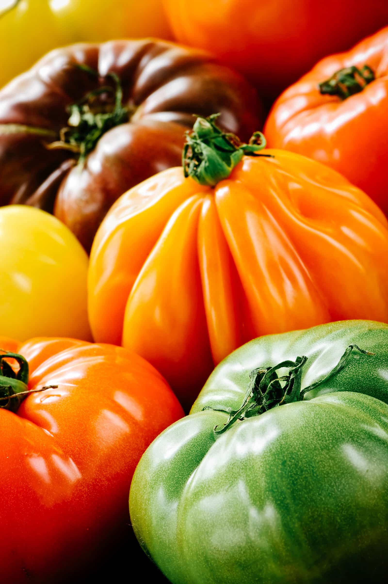Close-up of green, red, orange, yellow, and black heirloom tomatoes clustered together