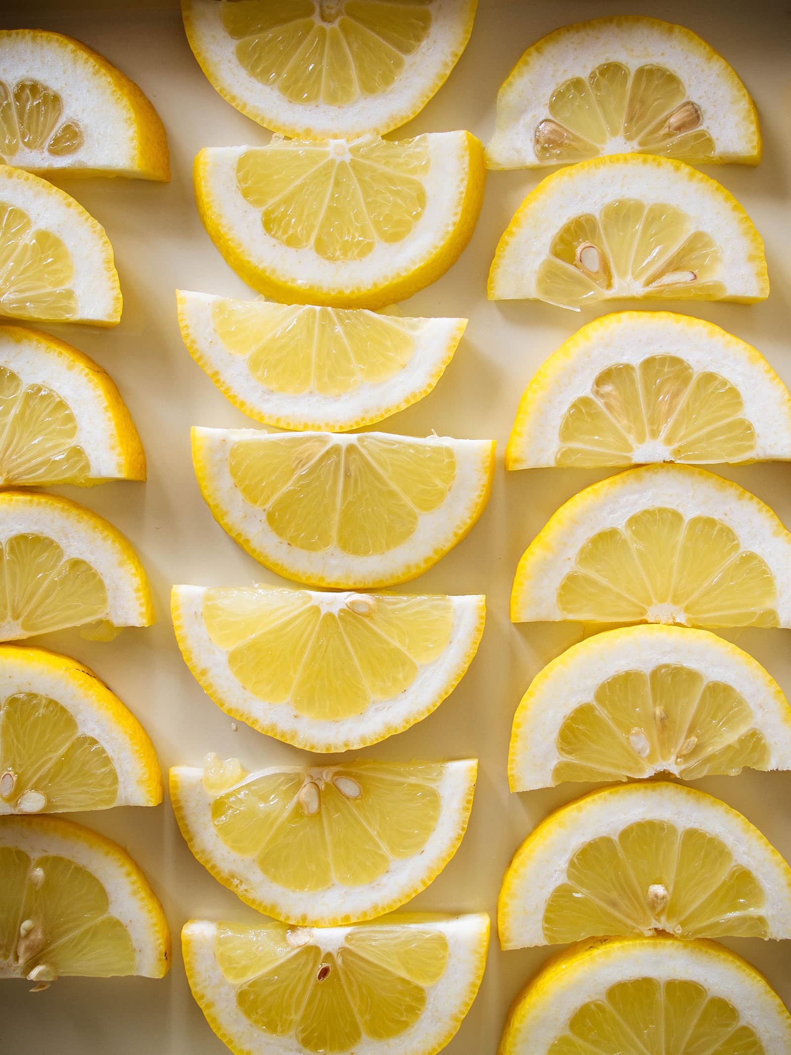 Overhead shot of lemon half-slices arranged in rows on a baking tray