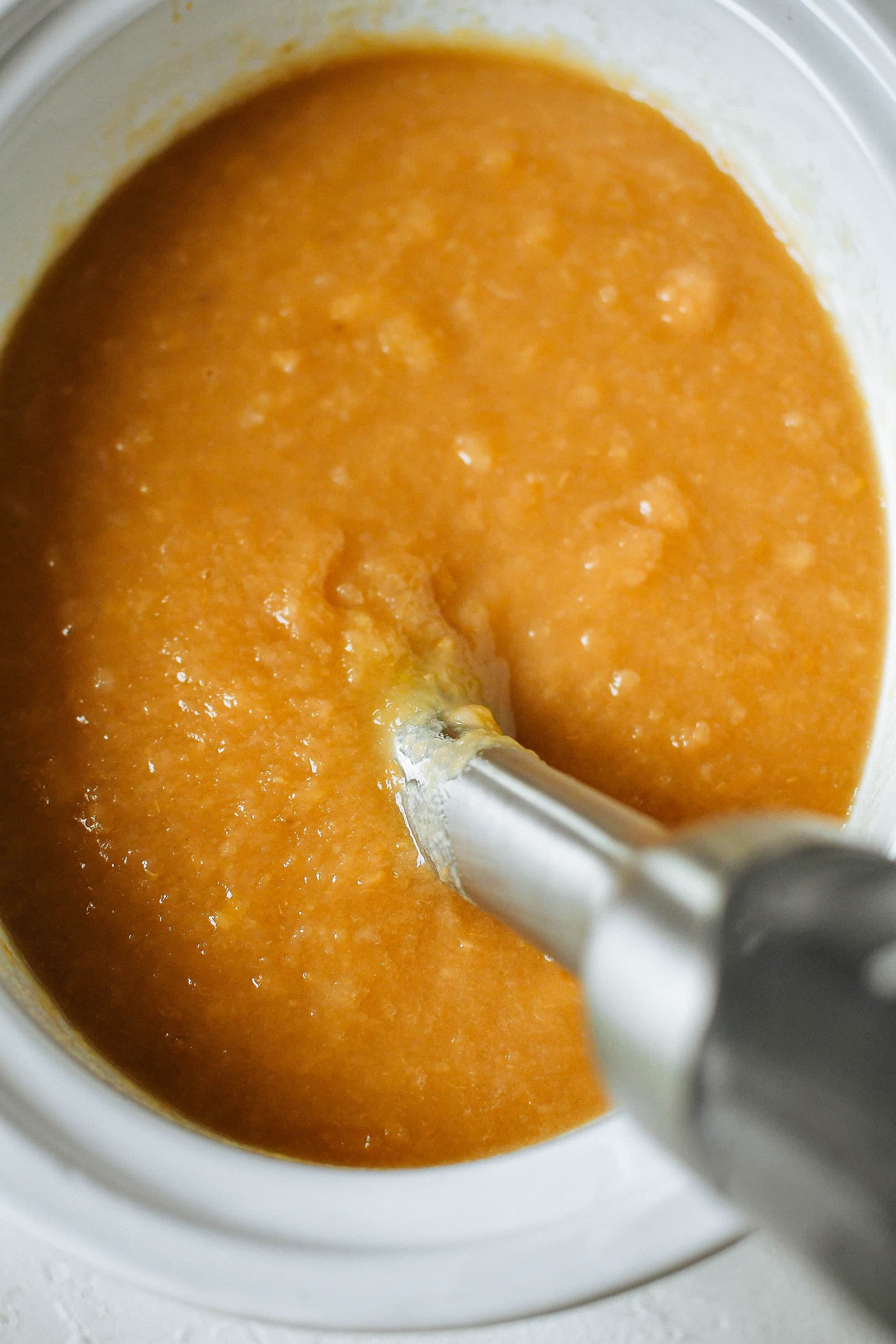 Immersion blender in a crockpot filled with an apple and pear mixture