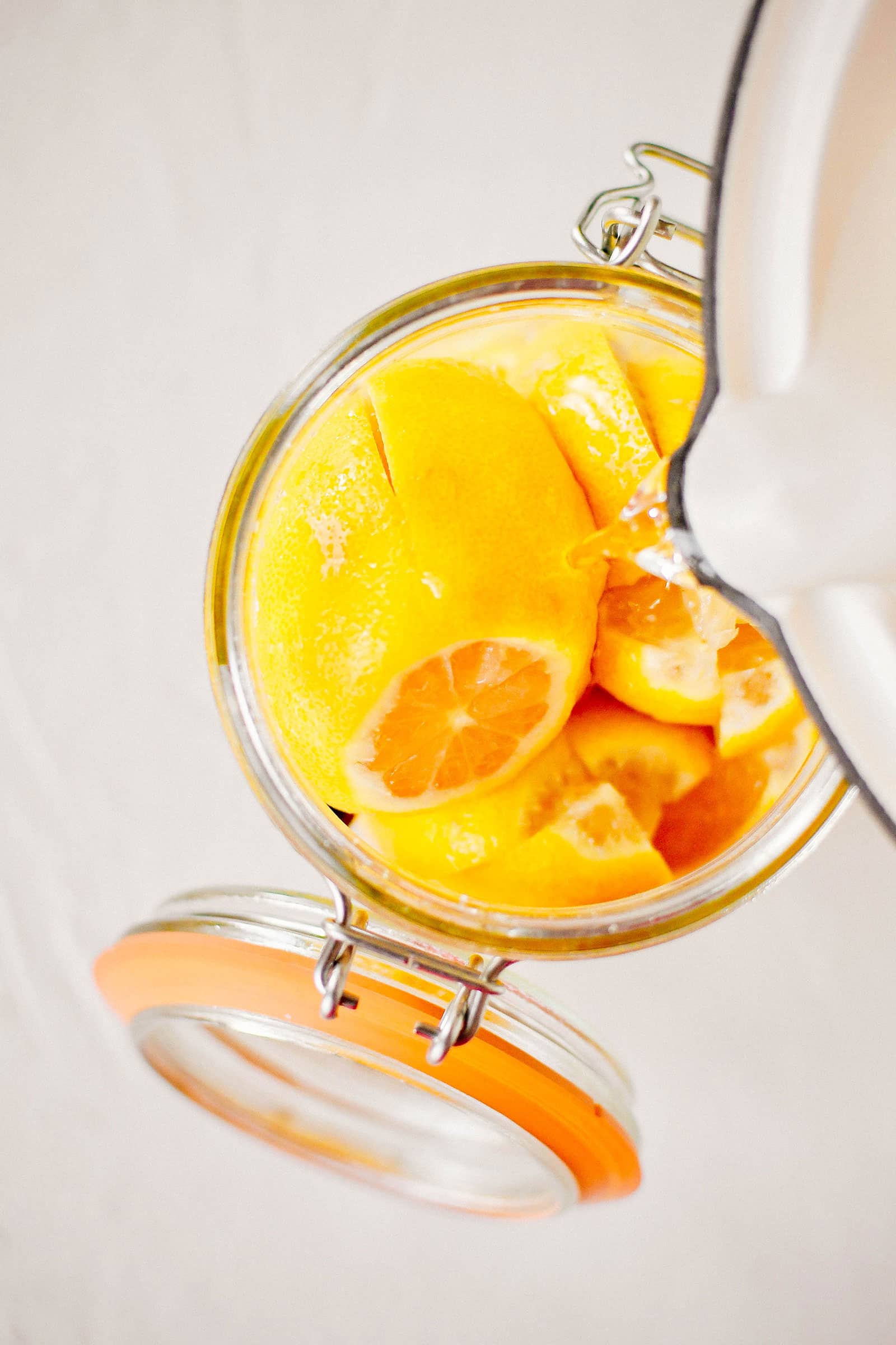 Hot brine pouring into a jar filled with cut lemons