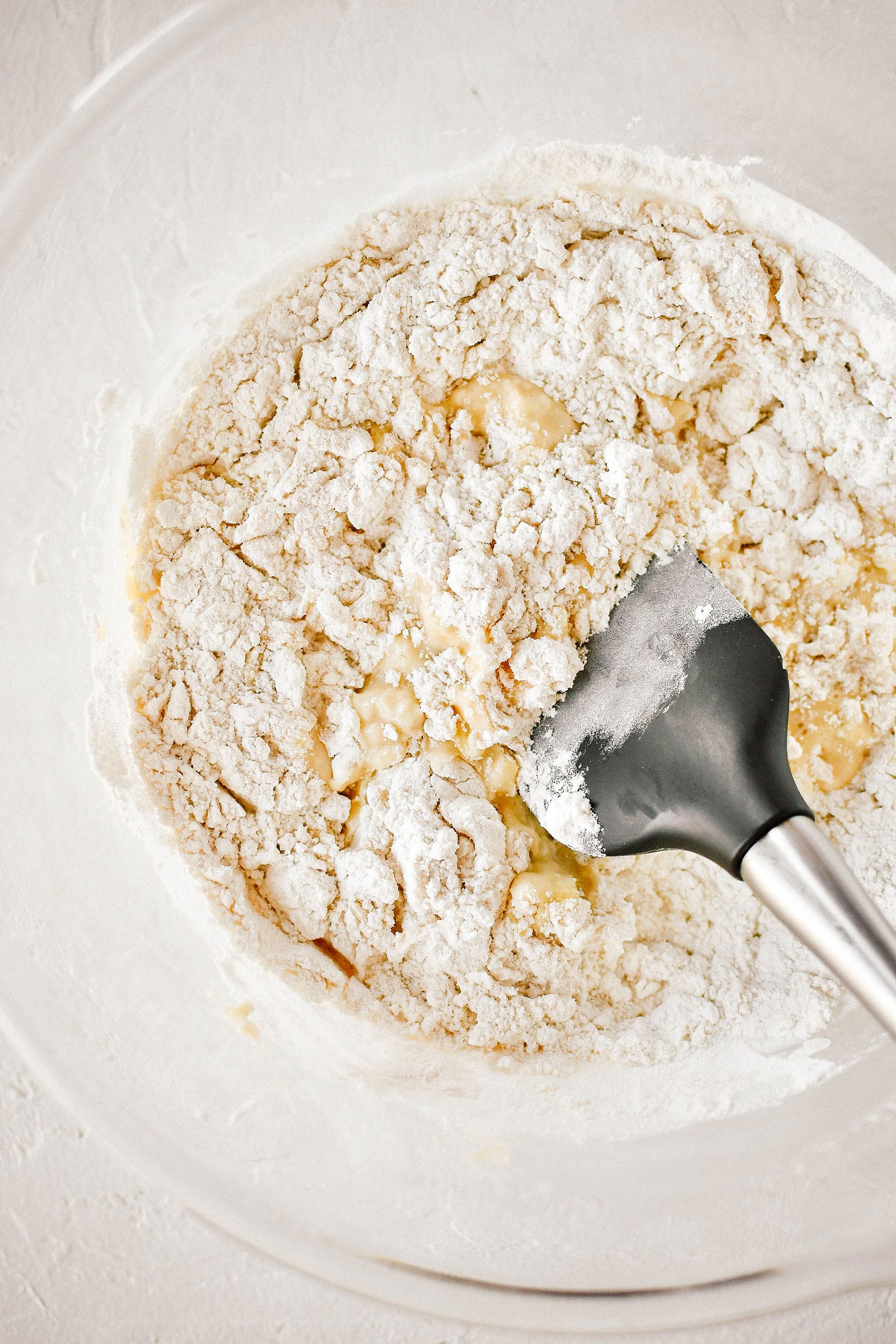 A spoon mixing dry ingredients into wet ingredients in a bowl