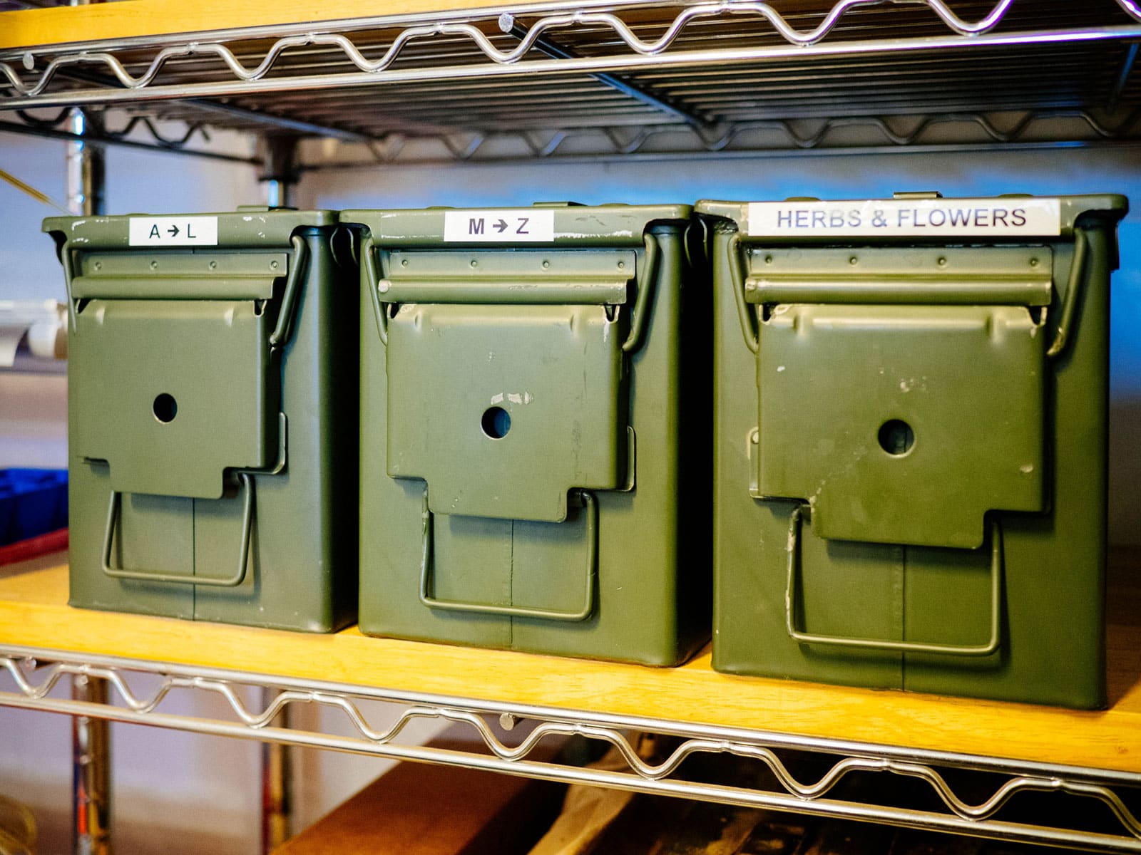 Metal ammo cans on wooden shelves in a workbench